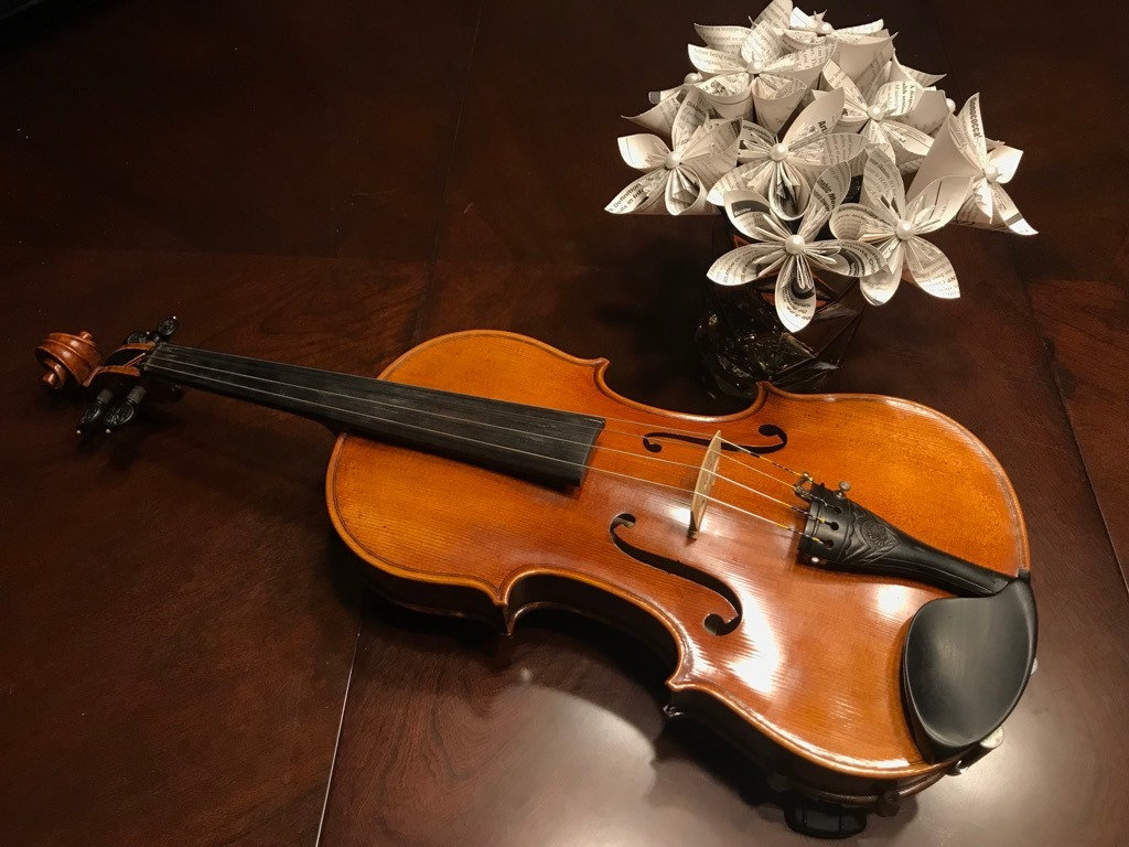 A small bouquet of paper flowers next to a viola.